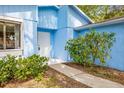 Inviting entryway with a blue exterior, a white door, and mature landscaping at 770 Arthurs Ct, Tarpon Springs, FL 34689