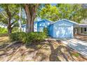 Attractive single-story blue home featuring well-maintained landscaping and an attached garage at 770 Arthurs Ct, Tarpon Springs, FL 34689