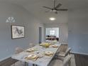 Dining room with a marble table set for six, a modern ceiling fan, and wood laminate flooring at 807 Nectar Rd, Venice, FL 34293