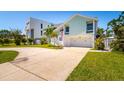 Beautifully landscaped home featuring a two-car garage, grassy yard, and a welcoming entrance with an American flag at 118 Wall St, Redington Shores, FL 33708