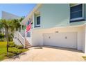 Exterior view of garage entrance with adjacent staircase and small garden with view of American Flag at 118 Wall St, Redington Shores, FL 33708