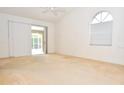Bright bedroom featuring sliding doors, an arched window, neutral carpet and a ceiling fan at 3876 Darston St, Palm Harbor, FL 34685
