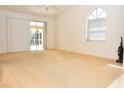 Bright living room with vaulted ceiling, large window, sliding glass door and neutral carpet creates an open and airy space at 3876 Darston St, Palm Harbor, FL 34685
