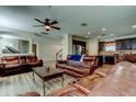 Spacious living room featuring wood-look floors, ceiling fan, recessed lights, and comfortable leather furniture. Open floor plan at 4250 Warwick Hills Dr, Wesley Chapel, FL 33543
