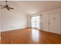 Bright living room with hardwood floors, white walls, a ceiling fan, and large windows offering natural light at 7934 Aden Loop, New Port Richey, FL 34655