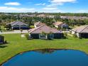 Aerial view of a home with lush lawn, mature trees, beautiful landscaping, and community lake at 15635 Sacile Ln, Bradenton, FL 34211