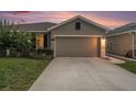 Single-Gathering home with gray stucco, concrete driveway, an attached garage, and landscaped yard at 18184 Turning Leaf Cir, Land O Lakes, FL 34638
