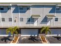 Townhome featuring white railings, individual entrances, and landscaped palm trees at 19823 Gulf Blvd # 33, Indian Shores, FL 33785