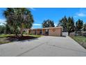 Tan house with well-maintained lawn, palm trees, and long driveway at 21838 Edgewater Dr, Port Charlotte, FL 33952