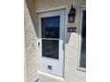 A close-up of the front door with screen, number plate, and exterior light fixture at 8707 Sailmaker Ct, Tampa, FL 33615