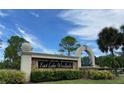 Stone sign for East Lake Woodlands, showcasing the community's entrance and landscaping at 10 Arbor Ln, Oldsmar, FL 34677