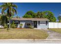 Cozy home featuring a well-kept lawn, palm trees, and a paved driveway, complemented by a white picket fence at 1541 68Th N Ave, St Petersburg, FL 33702