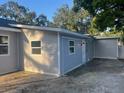 View of the side and rear of the house with light gray siding and an adjacent concrete driveway at 1574 Ewing Ave, Clearwater, FL 33756