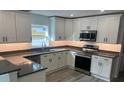 Modern kitchen featuring white cabinets, stainless steel appliances, and gray countertops at 1574 Ewing Ave, Clearwater, FL 33756