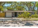 Charming single-story home featuring a gray exterior, attached garage, and a well-manicured front yard with tropical landscaping at 2515 Park N St, St Petersburg, FL 33710