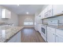 Well-lit kitchen featuring stainless steel appliances, white cabinets, granite countertops, and wood-look flooring at 3138 Clover Blossom Cir, Land O Lakes, FL 34638