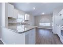 Bright kitchen boasts white cabinets, granite countertops, and wood-look flooring for a modern, stylish design at 3138 Clover Blossom Cir, Land O Lakes, FL 34638