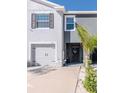 Close up of townhome featuring a pristine garage, dark front door and tropical landscaping at 34355 Sorrel Mint Dr, Wesley Chapel, FL 33543