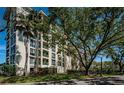 View of the building exterior showcasing multiple balconies, lush landscaping, and mature trees at 4801 Osprey S Dr # 508, St Petersburg, FL 33711