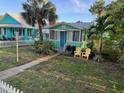 Quaint home with a blue door and bright yellow chairs, framed by lush palm trees and lawn at 5314 21St S Ave, Gulfport, FL 33707