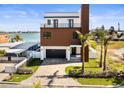 Waterfront modern two-story home featuring a balcony and a paved driveway at 109 Punta Vista Dr, St Pete Beach, FL 33706