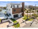 Modern two-story home featuring a balcony, a paved driveway, and tropical landscaping at 109 Punta Vista Dr, St Pete Beach, FL 33706