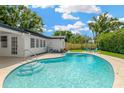 Backyard pool with a well-kept lawn and a house with a dark roof, offering a refreshing outdoor space at 11361 88Th Ave, Seminole, FL 33772