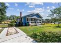 Quaint blue bungalow with a brick chimney, cozy porch, and well-maintained lawn on a sunny day at 2408 Linsey St, Tampa, FL 33605