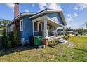 Quaint blue bungalow with a cozy porch, manicured lawn, and architectural details on a sunny day at 2408 Linsey St, Tampa, FL 33605