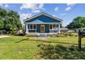 Charming blue home featuring a welcoming front porch, manicured lawn, and vibrant yellow door at 2408 Linsey St, Tampa, FL 33605