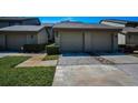 Townhome exterior with a two-car garage, green lawn, and trimmed hedges enhancing curb appeal in a well-maintained community at 3024 Landmark Blvd # 607, Palm Harbor, FL 34684