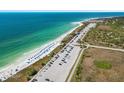 Aerial view of a white sand beach and turquoise ocean water with rows of cars in parking lot at 5 Island Park Pl # 305, Dunedin, FL 34698