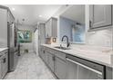 Modern kitchen features sleek gray cabinets, stainless steel appliances, and a stylish marble backsplash at 5 Island Park Pl # 305, Dunedin, FL 34698