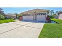 Charming home featuring a well-manicured lawn, lush landscaping, and a three-car garage at 5137 Epping Ln, Zephyrhills, FL 33541