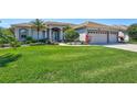Charming home featuring a well-manicured lawn, lush landscaping, and a three-car garage at 5137 Epping Ln, Zephyrhills, FL 33541