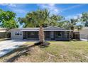 Neat one-story house featuring a well-kept lawn, palm tree, and a screened porch at 7101 Kingston Dr, Tampa, FL 33619