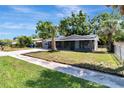 Quaint single-Gathering home with a lush green lawn and sidewalk leading to the front porch at 7101 Kingston Dr, Tampa, FL 33619