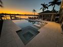 Outdoor oasis with a luxurious pool and spa, plus covered seating area and stunning water views at sunset at 714 Bayshore Dr, Tarpon Springs, FL 34689