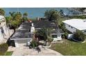 Aerial view of a home with a dark roof surrounded by lush greenery near a bay at 15507 Redington Dr, Redington Beach, FL 33708