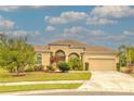 Charming single Gathering home showcasing its manicured lawn, mature landscaping, and an attached two car garage at 2218 132Nd E Pl, Parrish, FL 34219