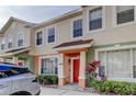 Charming townhome featuring colorful stucco, manicured landscaping, and covered entryway to the vibrant red front door at 263 Alexander Woods Dr, Plant City, FL 33563