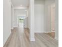 Bright hallway with light wood flooring, white walls, and a glimpse of the outdoors with a staircase at 31651 Westbury Estates Ave, Wesley Chapel, FL 33545