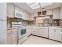 Bright kitchen with white appliances, tile backsplash, wine rack, and a window looking into another living area at 3610 Magnolia Ridge Cir # 1322/H, Palm Harbor, FL 34684