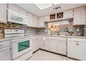 Bright kitchen with white appliances, tile backsplash, wine rack, and a window looking into another living area at 3610 Magnolia Ridge Cir # 1322/H, Palm Harbor, FL 34684