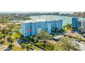 Condo building exterior featuring a parking lot and tropical landscaping at 610 Island Way # 302, Clearwater Beach, FL 33767