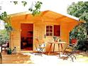 Cozy wooden cabin with an outdoor sitting area and a well-maintained deck under the shade of leafy trees at 7006 41St E Ave, Bradenton, FL 34208