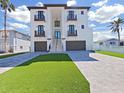 Modern three-story home boasts a beautiful facade, two garages, and well manicured landscaping with artifical turf at 882 Bay Point Dr, Madeira Beach, FL 33708