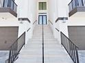 Close-up of the front entrance with grand staircase, black railings, and modern exterior lighting at 882 Bay Point Dr, Madeira Beach, FL 33708