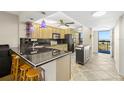 Open kitchen featuring modern appliances, dark countertops, and ample cabinet space, adjacent to balcony access at 9415 Blind Pass Rd # 704, St Pete Beach, FL 33706