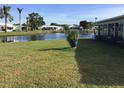Waterside backyard featuring a green lawn with view of canal and neighboring houses at 1002 Pussywillow Ln, Bradenton, FL 34208